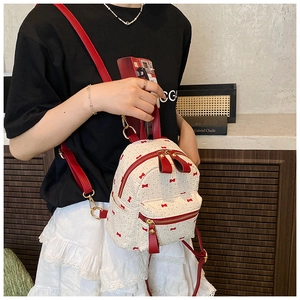 Detailed close-up of mini backpack featuring woven texture and red bow patterns