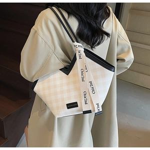 Close-up of checkered tote bag with black leather straps and fashion ribbon detail