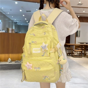 Detailed view of light yellow quilted backpack featuring ribbon bows and moon plush charm