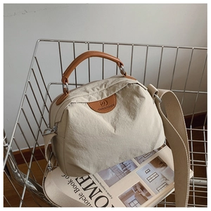 Dettaglio della borsa tote in nylon beige con manici in pelle marrone e tracolla regolabile