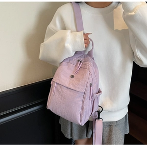 Detail showing the lavender nylon backpack with front flap pocket on a fashion model