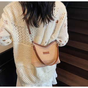 Dettaglio di una borsa a tracolla in maglia a righe con trama crema e cinturino marrone