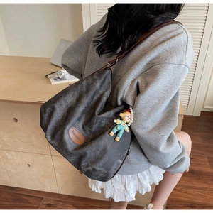 Détail du sac cabas en toile vintage avec écusson en cuir brun et porte-clé poupée