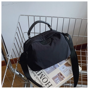 Dettaglio borsa a tracolla in nylon nero con tracolla regolabile e logo in rilievo