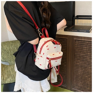 Detail of white woven mini backpack with red bow embroidery and adjustable leather straps