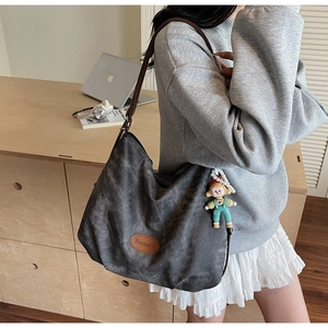 Détail du sac hobo en toile grise avec logo Banatu en cuir et breloque poupée