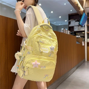 Detail of yellow quilted backpack with plush star embroidery and cute cartoon pendant