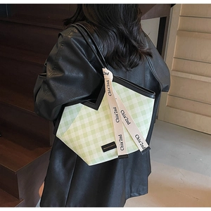 Detail view of large green and white checkered tote bag with wide branded straps