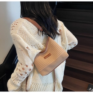 Dettaglio della borsa a tracolla in maglia beige con finiture in pelle marrone e logo