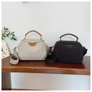 Borse a tracolla minimaliste in nylon beige e nero esposte su una superficie in legno