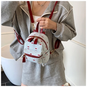 Close-up of light blue mini backpack with red bow print and golden metal zipper detail