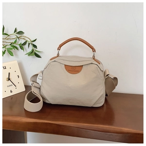 Dettaglio borsa tote in nylon beige con manici in pelle marrone e tracolla larga