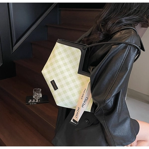 Fashionable green checkered tote bag worn by model on a modern staircase background