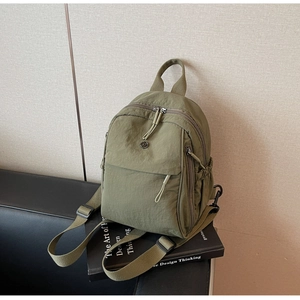 Close-up of olive green nylon backpack with metal logo and zipper detail on books