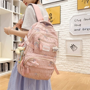 Detail of pink fabric backpack featuring embroidered bows and 3D textured patterns