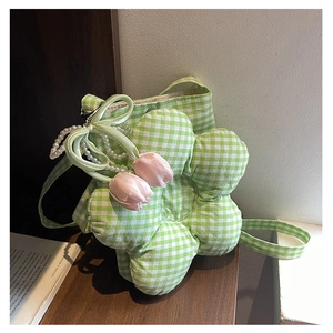 Close-up of green checkered flower-shaped bag with pearl handle and tulip charm detail