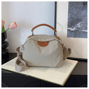 Dettaglio della borsa in nylon minimalista con logo in pelle marrone e tracolla regolabile