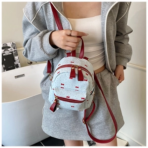Lifestyle shot of a light blue bow-patterned mini backpack with red leather straps