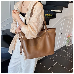 Detailed close-up of a large brown leather tote bag with elegant metal ring and shoulder strap