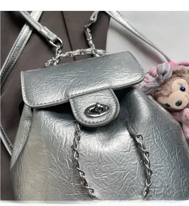 Makro-Detail des silbernen Rucksacks mit metallischem Drehverschluss und Ketten-Griff