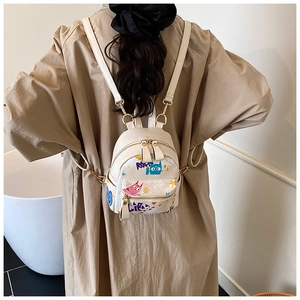 Détail d'un mini sac à dos blanc en cuir PU avec motifs graffiti colorés et zips dorés