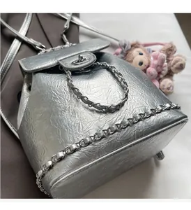 Detailansicht des silbernen Metallic-Rucksacks mit Kettenriemen und Klappenverschluss
