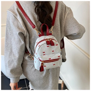 Detail of blue mini backpack with red bow pattern and contrast leather straps