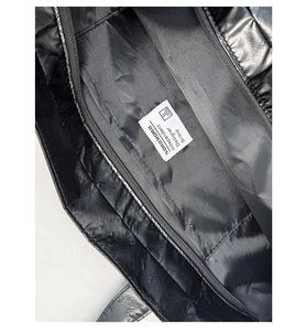 Macro view of a black quilted tote bag showing interior zipper and designer label