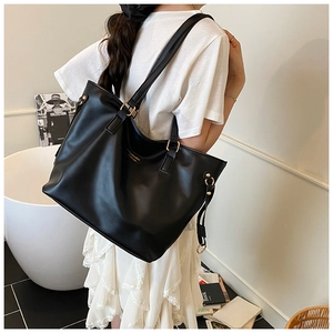 Detailed view of the large black tote bag showing smooth leather texture and gold buckles