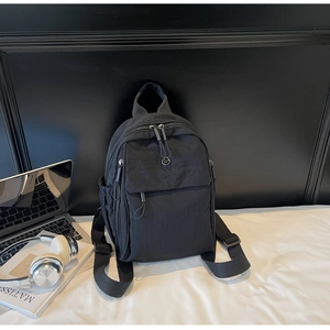 Detailed view of black waterproof nylon backpack with metal JV logo and side pocket