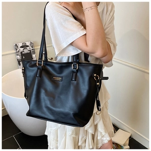 Close-up of black matte tote bag with adjustable straps and golden metal hardware details
