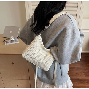 Detail of white striped knit crossbody bag showing woven texture and shoulder strap