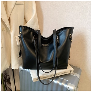 Close-up of black leather tote bag with gold logo on a silver suitcase