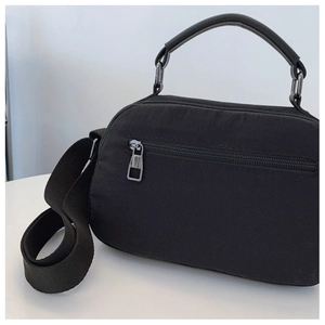 Dettaglio della borsa a tracolla in nylon nero con trama impermeabile e tasca con cerniera