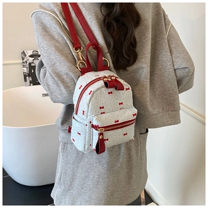 Close-up of cream mini backpack with red bow prints and waffle textured fabric for women