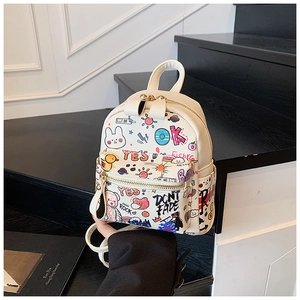 Détail d'un mini sac à dos crème avec des graffitis colorés et des motifs d'oursons