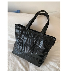 Détail d'un cabas noir brillant en nylon avec poche zippée et broderie élégante