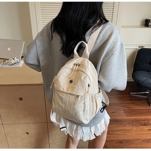 Detail of beige multi-pocket backpack with adjustable straps worn by a model in office