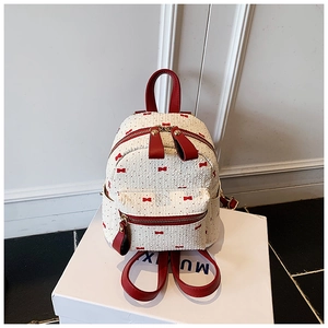 Detail of white textured mini backpack with red bow print and leather straps