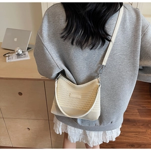 Dettaglio della borsa a tracolla in maglia crema con cinturino in pelle e patch con logo