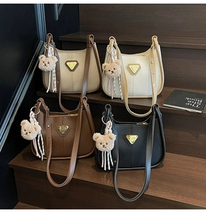 Détails de quatre sacs hobo en cuir coloré avec breloques d'ours et logos sur des marches