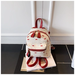 Detail of white waffle fabric backpack featuring red bow prints and leather straps