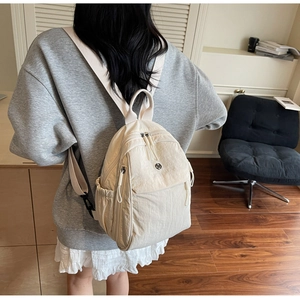 Creamy nylon backpack shown from a back view with wide straps and smooth fabric