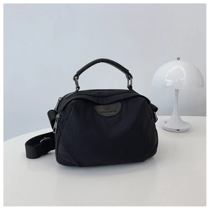 Dettaglio della borsa a tracolla in nylon nero con logo e lampada a fungo di design
