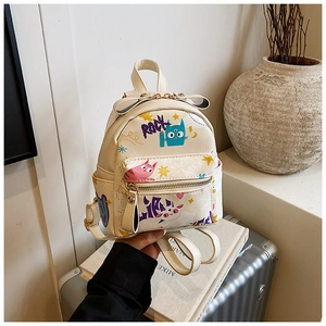 Détail d'un mini sac à dos en cuir PU beige avec graffiti de chat et décoration de nœud
