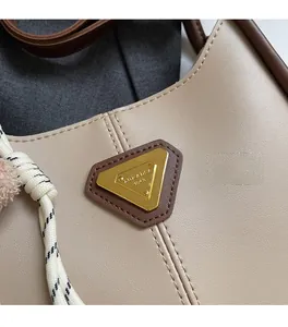 Vue macro d'un sac en cuir beige avec logo triangle doré et détail de corde tressée