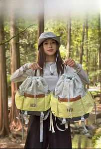 Outdoor view of multi-color drawstring backpacks in yellow and gray waterproof nylon fabric