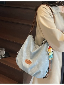Grand sac cabas bleu clair avec lanières marron et pendentif porté par un mannequin