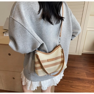Detail of striped knitted crossbody bag featuring brown leather straps and woven texture