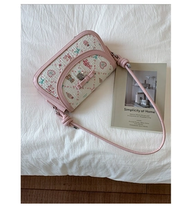 Detailed close-up of a pink ballet-style crossbody bag with cute bear and heart patterns